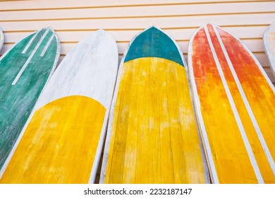 Several surfboards of different colorful saturated yellow, green, red colors lined up against the wall - Shutterstock ID 2232187147