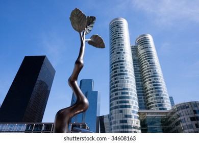 Several tall buildings in Paris, France in La Defense district. Bronze branch is in front of the picture,