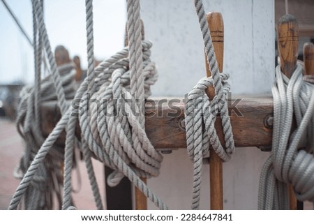 several thick cotton ropes lashed off at a common point on the main deck of a historic sailing ship that requires a large crew of skilled sailors to leave port and go on a voyage