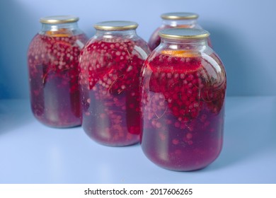 Several Three-liter Cans Of Currant And Orange Compote Stand On A Blue Background