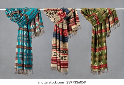 Several tied scarves with fringe on a hanger. Home comfort. Colorful plaids on a gray background. - Powered by Shutterstock