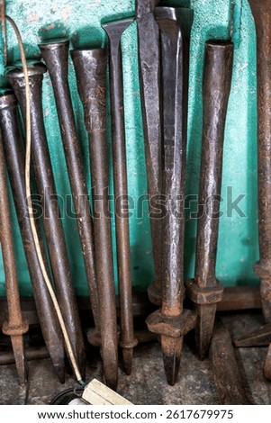 Several tips of metal chisel tools on a copper and brass workshop.