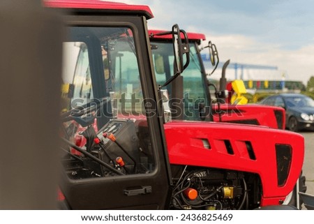 Several tractors are parked in a neat row next to each other in a field or farmyard.