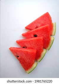 Several triangular-shaped bright red watermelon pieces are stacked on a white background.