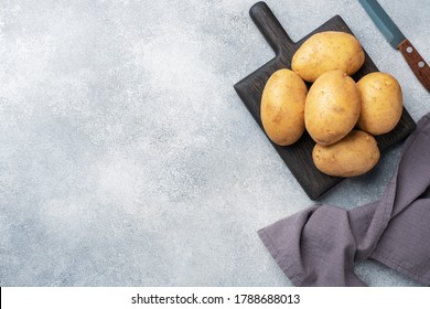 Mehrere Knollen roher Kartoffeln auf grauem Betonhintergrund. Kopiert Platz.