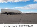 Several twin-engine multirole fighter jets parked in open shelters on an airbase apron under a clear sky