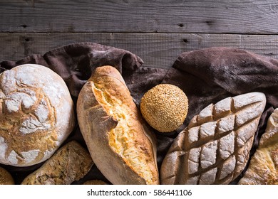 Several types of fresh bread lying on an old wooden table