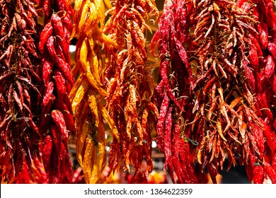 Several varieties of dried hot chili peppers hanging from a open market in Spain. Smoke  over heat, and then grind dried chili peppers for blends and rubs or reconstitute in water for salads or salsa.