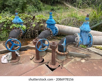 Several water pipelines pump or suck raw water from rivers for processing at a water processing plant. Pipelines and valves with blue wheels system. Pipe valve water plant. Selective focus.