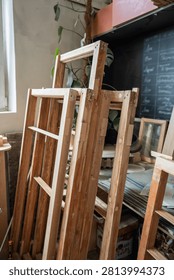 Several window frames stacked at carpentry workshop room after replacement of wooden parts, restoration of wooden items in woodworking studio, furniture renovation, handmade craft and reconstruction.