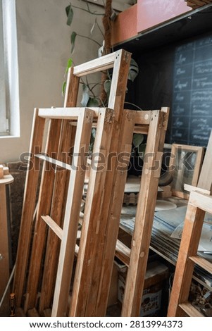 Several window frames stacked at carpentry workshop room after replacement of wooden parts, restoration of wooden items in woodworking studio, furniture renovation, handmade craft and reconstruction.