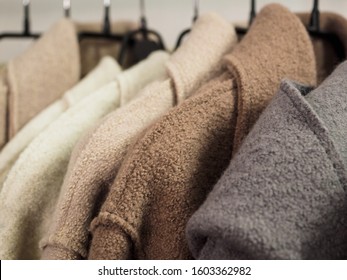 Several wool coats hanging on a hanger in the store.