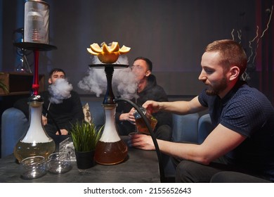 several young men are smoking a hookah, in front of him is a bowl of hookah with grapefruit. atmospheric cafe with hookah