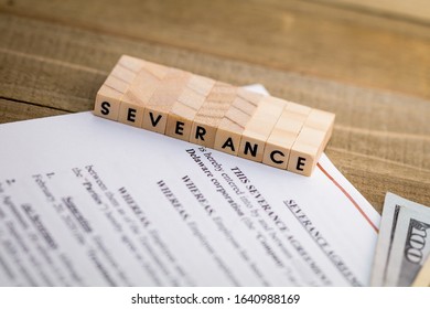 Severance Pay concept with agreement document on wooden board and SEVERANCE spelled out in wood blocks selective focus