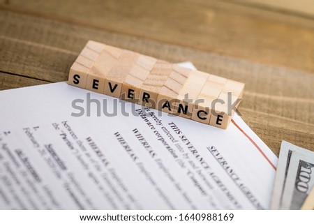 Severance Pay concept with agreement document on wooden board and SEVERANCE spelled out in wood blocks selective focus