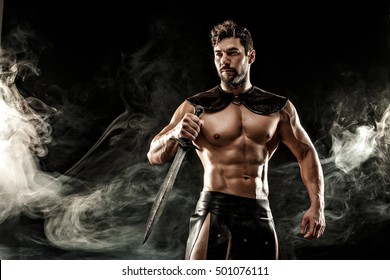 Severe barbarian in leather costume with sword in smoke
