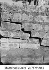 Severe structural failure in a red brick wall due to foundation settling, Aged red brick wall with significant cracks and