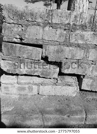 Severe structural failure in a red brick wall due to foundation settling, Aged red brick wall with significant cracks and
