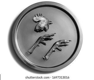 Severed Dead Animal Parts: Butchered Raw Chicken Rooster Head And Legs On Silver Tray Like An Ikon Or Logo Symbolizes Meat Eating ; Black And White Close Up Photo.
