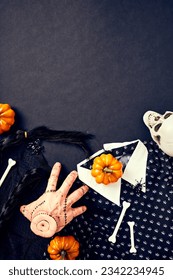 Severed hand Thing from Addams Family, Wednesday dress and hair braids, spiders, bones, orange pumpkins on dark background. Halloween holiday celebration.