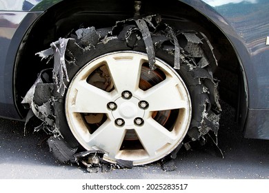 Severely blown tire on car shredded to pieces. - Shutterstock ID 2025283517