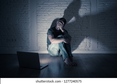 Severely distraught young men with laptop suffering cyberbullying and harassment being online abused by stalker or gossip feeling desperate and humiliated in cyber bullying and social media concept.