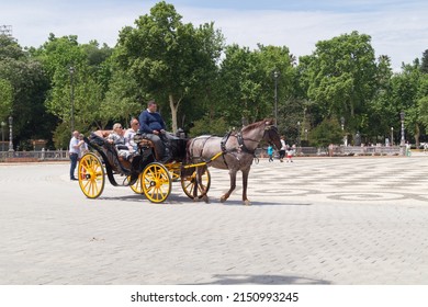 Seville, Andalusia, Spain; April 26th 2022: Older Couple Riding Around The Plaza De España In A Horse-drawn Carriage. Tourist Couple Sitting In A Carriage In A Tourist Area Of The City On A Sunny Day.