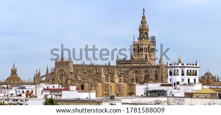 Seville Cathedral - A panoramic rooftop view of the roof of Seville Cathedral, with La Giralda tower rising high at behind, on a sunny Autumn day. Seville, Andalusia, Spain.