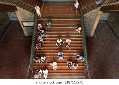 Seville, Spain - July 22, 2022: Exhausted Tourists Sitting On A Staircase At Plaza De España During A Hot Summer Day. 