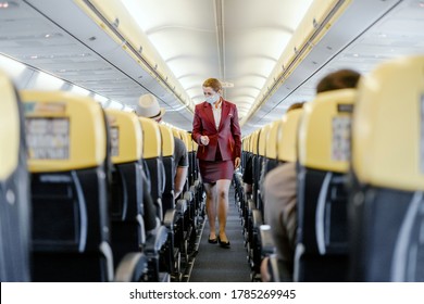 Seville, Spain - July 25, 2020: Stewardess With Face Mask Walking In  Airplane Cabin Among Passengers