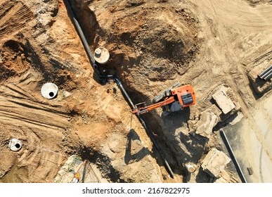 Sewage drainage system mounting at construction site. Excavator during laying sewer pipe and main systems. Civil infrastructure, water lines, sanitary sewers and storm sewers. Laying sewer pipes.