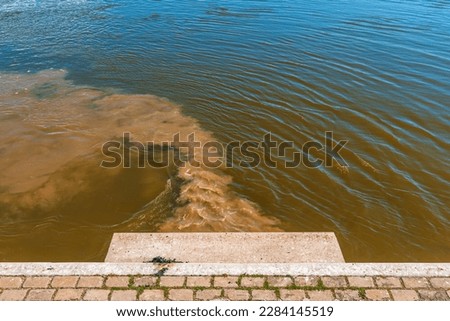 Sewage pipe outfall into the river, water pollution and environmental damage concept, selective focus