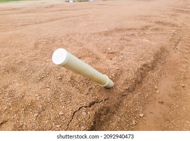 A sewage pipe sticking out of the ground and poorly covered