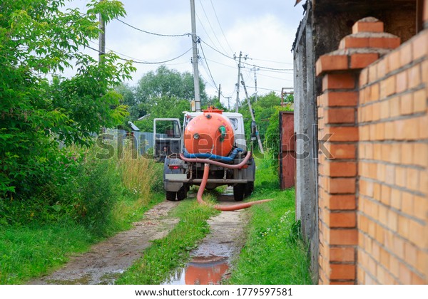 A Sewage\
truck working in village\
environment.