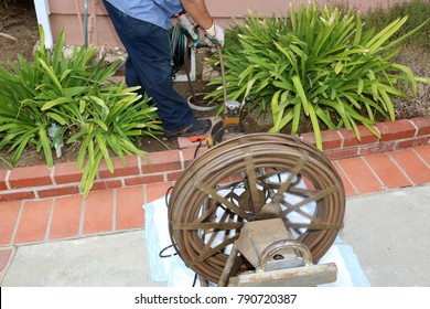 Sewer Cleaning. A Plumber Uses A Sewer Snake To Clean Blockage In A Sewer Line. 