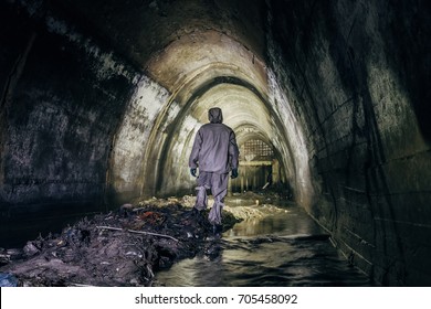Sewer tunnel worker in special chemical protective suite in underground gassy sewer tunnel