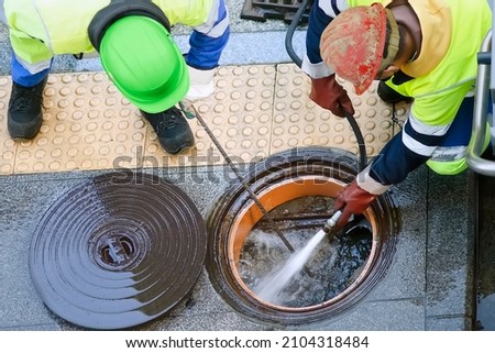 sewer  utility worker for cleaning and repairing sewerage pipes  in city street