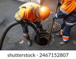 Sewer workers cleaning manhole and unblocking sewers the street sidewalk.