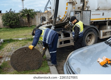Sewer workers cleaning manhole and unblocking sewers the street sidewalk.