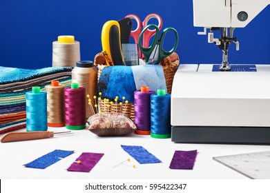 Sewing accessories in a basket and spools of threads next to sewing machine