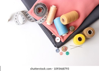 Sewing Accessories And Fabric On A White Background. Sewing Threads, Needles, Pins, Fabric, Buttons And Sewing Centimeter.
 Top View, Flatlay