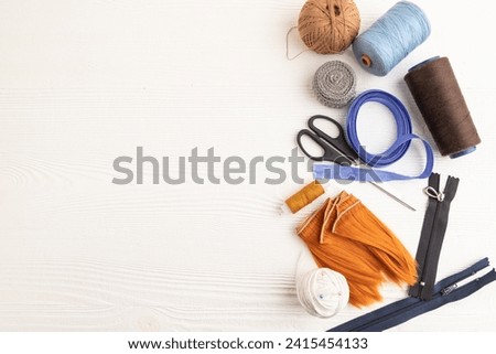 Sewing accessories: scissors, thread, thimbles, braid on white wooden background. Top view, flat lay, copy space