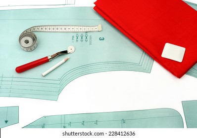 Sewing background. Sewing accessories and red fabric on a paper pattern.