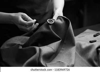 Sewing the buttons to the jacket. Tailor atelier - handmade exclusive clothes making and repair, private business, creative occupation concept