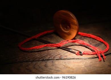 Sewing concept.Closeup of button and needle with thread on dark wooden background