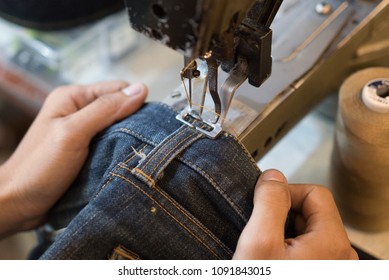 Sewing denim jeans with sewing machine. Repair jeans by sewing machine. Alteration jeans, handmade garment industrial concept.