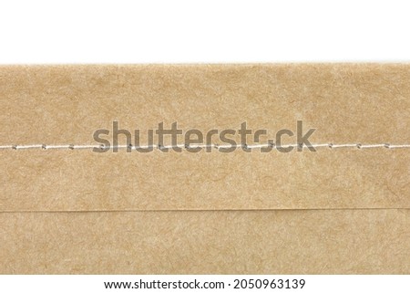 Sewing edge of brown paper on white background.
