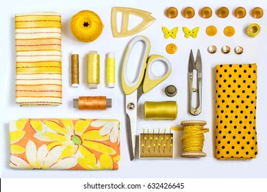 Sewing kit accessories and equipment for sewing yellow shades. Various sewing accessories and tools for needlework: fabric, threads, scissors, buttons, needles, braid, ribbons. Flat lay, top view - Powered by Shutterstock