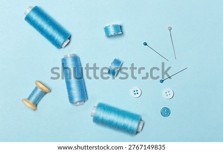 Sewing kit, blue threads on spools and sewing bobbins, buttons, top view.