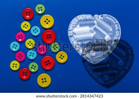 Sewing kit, bobbins with colored threads and measuring tape on a bright background with sewing buttons.
